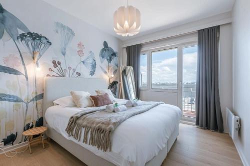 Schlafzimmer mit einem weißen Bett und einem großen Fenster in der Unterkunft Bright seaview apartment in Oostende in Ostende