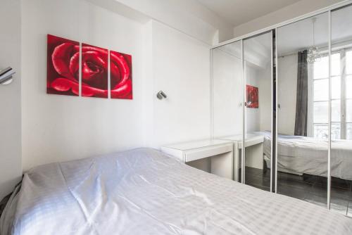 une chambre blanche avec un lit et un miroir dans l'établissement Paris St Germain Luxembourg, à Paris
