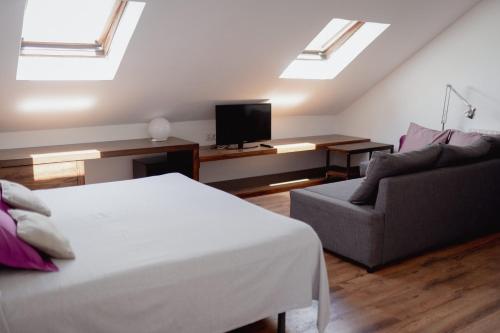 ein Schlafzimmer mit einem Bett, einem Sofa und Oberlichtern in der Unterkunft Cal Portalé in Claverol