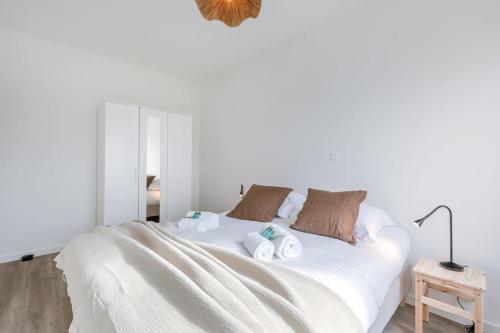 a white bedroom with a bed with towels on it at Brand new apartment with stunning harbor views in Bruges