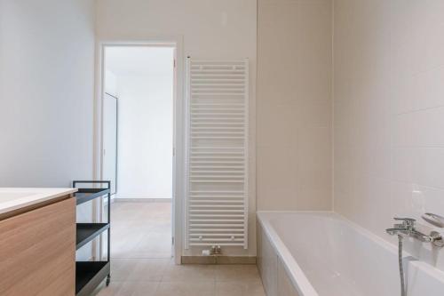Baño blanco con bañera y lavamanos en Brand new apartment with stunning harbor views en Bruges