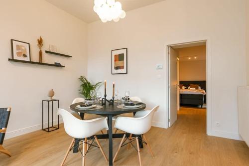 ein Esszimmer mit einem schwarzen Tisch und weißen Stühlen in der Unterkunft Huswell - Modern apartment located at historical Main Square in Antwerpen