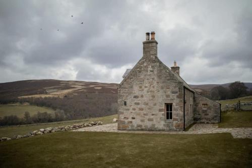 an old stone building on a grassy hill at Inverenzie - Luxury farmhouse with mountain views 