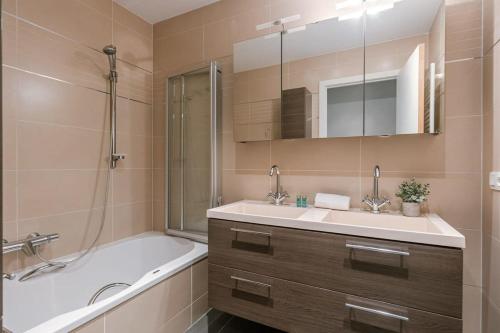 ein Badezimmer mit einer Badewanne, einem Waschbecken und einer Badewanne in der Unterkunft Spacious apartment with lateral sea view in Blankenberge