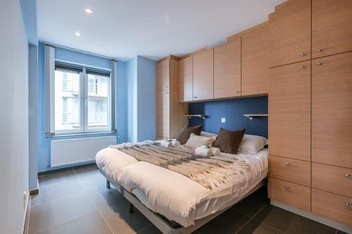 Schlafzimmer mit einem großen Bett und Holzschränken in der Unterkunft Spacious apartment with lateral sea view in Blankenberge
