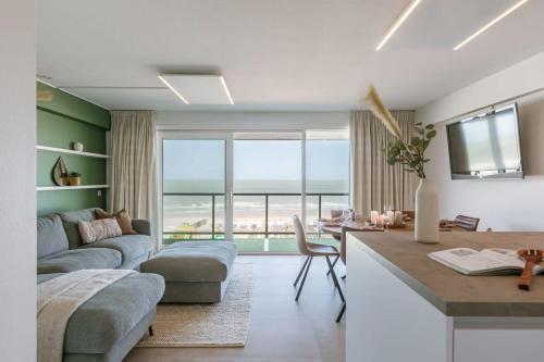 ein Wohnzimmer mit einem Sofa und eine Küche mit einem Tisch in der Unterkunft Frontal seaview apartment in Blankenberge in Blankenberge