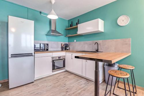 - une cuisine avec des appareils électroménagers blancs et des murs bleus dans l'établissement Atlas - Superbe logement plein centre - Terrasse, à Nîmes