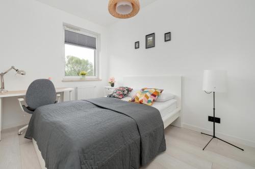 a white bedroom with a bed and a desk at Bright Apartment with Balcony Close to the Poniatowski Park Łódź by Renters in Łódź