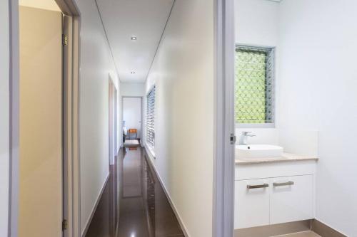 a hallway leading to a bathroom with a sink at On the very top of Cairns - Luxurious Entertainer in Bayview Heights