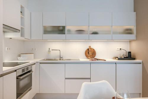 a white kitchen with white cabinets and a sink at Huswell - Modern apartment in heart of Knokke with terrace in Knokke-Heist