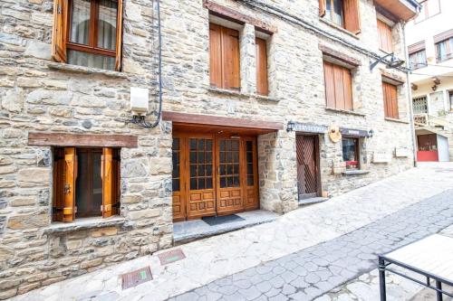 a stone building with a wooden door on a street at Rural apartment in the mountains in Panticosa