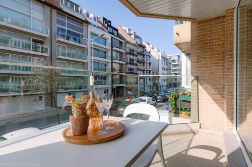 a table with a wine bottle and glasses on a balcony at Huswell - Apartment for 4 near the coast and central Knokke in Knokke-Heist
