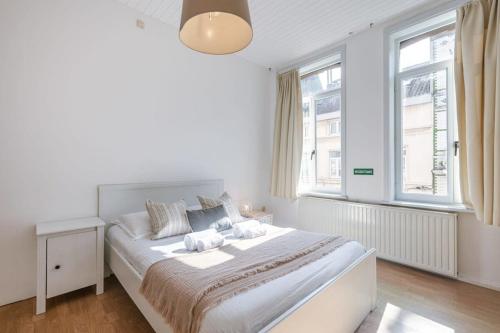 - une chambre blanche avec un grand lit et 2 fenêtres dans l'établissement Spacious vacation home 'Huis Lapon', à Ostende