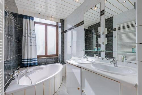 La salle de bains blanche est pourvue de 2 lavabos et d'une baignoire. dans l'établissement Spacious vacation home 'Huis Lapon', à Ostende