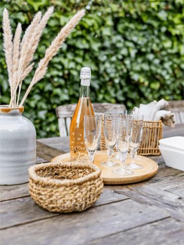 a table with wine glasses and a bottle on it at Huswell - Authentic vacation home 'De Blauwe Kroon' in Oostkamp