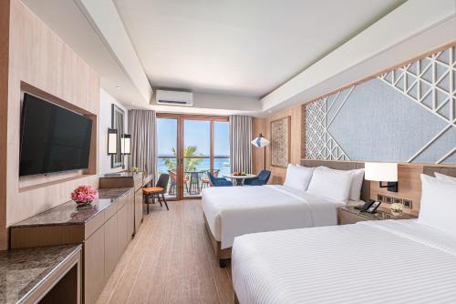 um quarto de hotel com duas camas e uma televisão em Henann Premier Coast Resort em Panglao