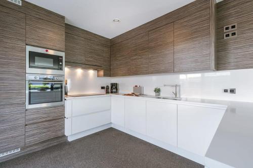 a kitchen with white cabinets and wooden walls at Huswell - Spacious house with garden and parking in Blankenberge