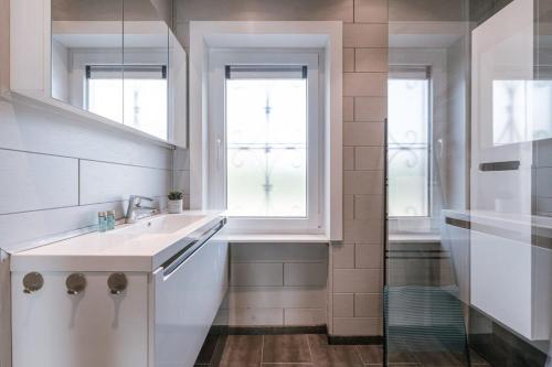 a white bathroom with a sink and a window at Huswell - Spacious house with garden and parking in Blankenberge