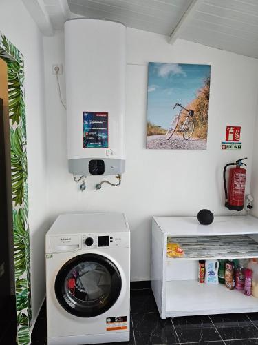 a laundry room with a washing machine and a microwave at SB Alojamento in Amora