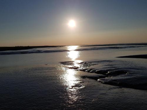 a sun setting over the water on a beach at Bed & Breakfast Rheiderland in Ditzumerverlaat