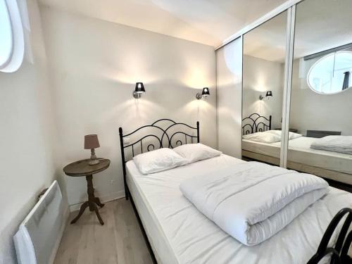 une chambre blanche avec un lit et un miroir dans l'établissement Joli appartement en centre ville, à Bagnères-de-Bigorre