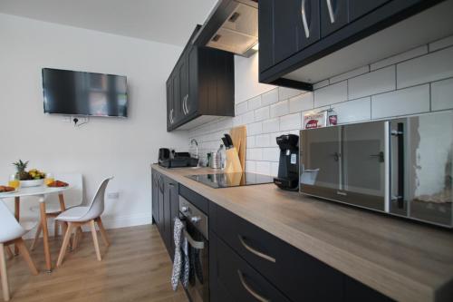 a kitchen with black cabinets and a counter top at Superb 1-Bed Apartment - Free Parking Dundee in Dundee