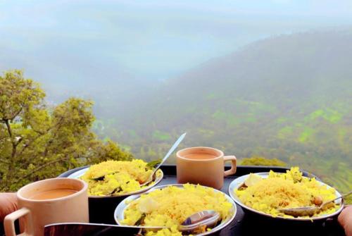 a table with three plates of food and two cups of coffee at Kalasita in Mahabaleshwar