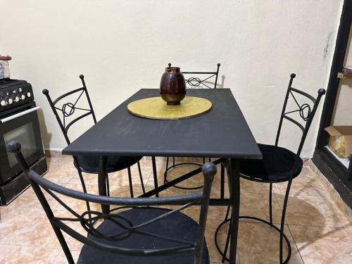 une table noire avec des chaises et un vase sur elle dans l'établissement Appartement à côté de l'aéroport, à Marrakech