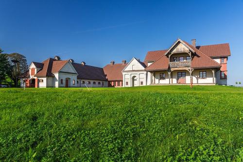 una casa grande con un césped verde delante de ella en Stadnina Koni Nad Wigrami, en Mikolajewo