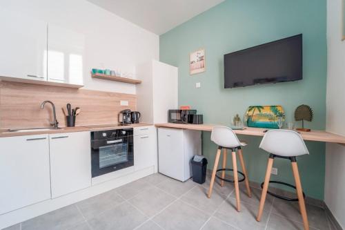 Il comprend une cuisine avec des placards blancs et une télévision murale. dans l'établissement Atlas - Troie, à Saint-Thibéry