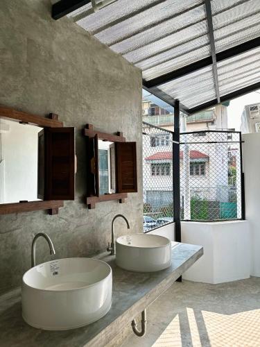 La salle de bains est pourvue de 2 lavabos et d'une grande fenêtre. dans l'établissement Sleep Owl Chiang Mai, à Chiang Mai