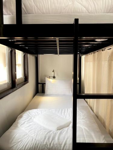a bedroom with two bunk beds with white sheets at Sleep Owl Chiang Mai in Chiang Mai