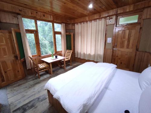 a bedroom with a bed and a table in it at The Forest Pinnacle and Café, Jibhi in Jibhi