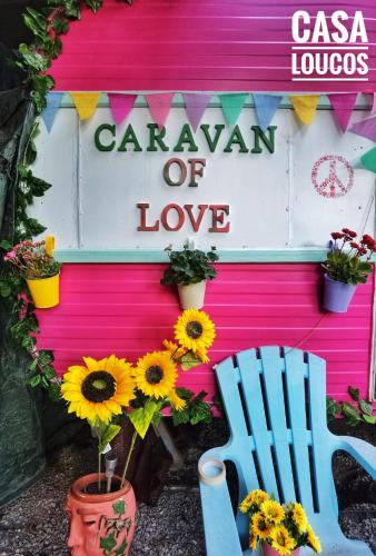 a garden of love sign on a pink wall with sunflowers at Caravan of Love by Casa das Artes in Luz de Tavira