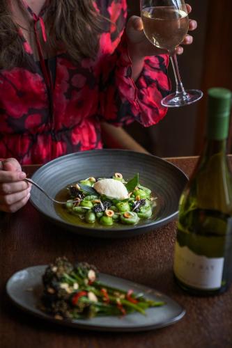 a woman sitting at a table with a plate of food and a wine glass at The Rodney Hotel in Bristol