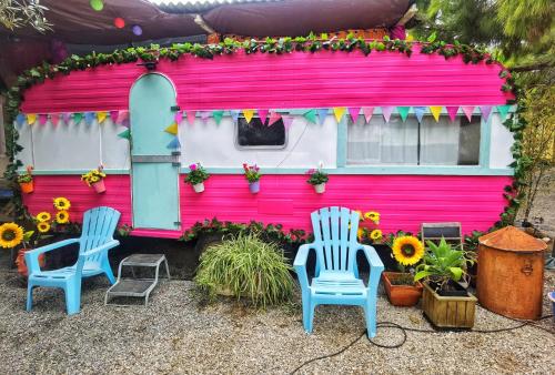 two chairs and a pink house with sunflowers at Caravan of Love by Casa das Artes in Luz de Tavira