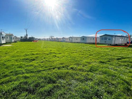 a large field of green grass with houses in the background at Charming Chamber with spacious relaxing area in Pagham