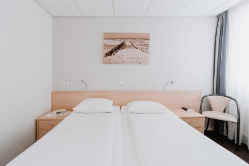 Hotel Kodde في آختيكيركي: غرفة نوم بسرير ابيض كبير وكرسي
