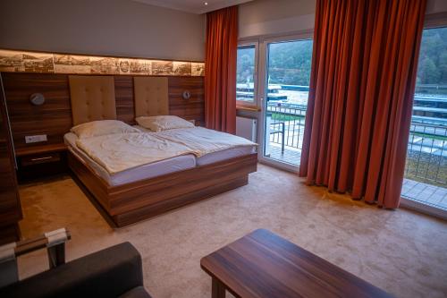 ein Schlafzimmer mit einem Bett und einem großen Fenster in der Unterkunft Hotel Unter den Linden in Rüdesheim am Rhein