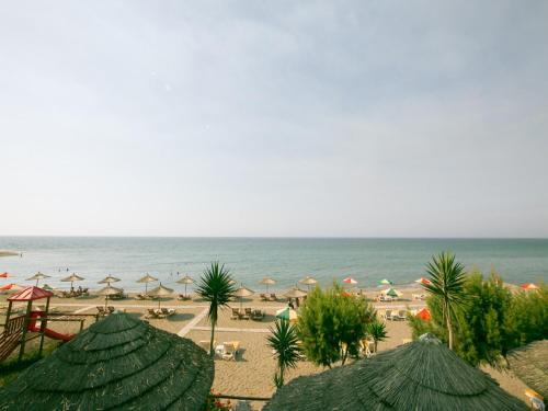 a beach with umbrellas and chairs and the ocean at Villa Russelia in Kalavárda