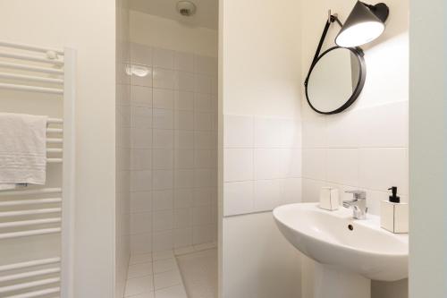 une salle de bain blanche avec un lavabo et un miroir dans l'établissement DIFY Berthelot - Jean Mace, à Lyon