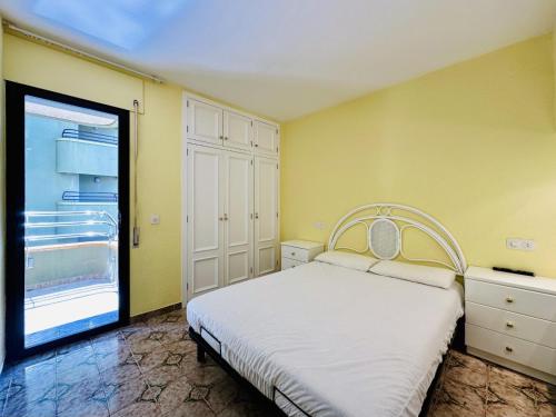 1 dormitorio con cama blanca y ventana grande en Apartament mar i vent, en Platja d'Aro