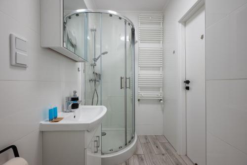 ein weißes Bad mit einer Dusche und einem Waschbecken in der Unterkunft Modern Space Cosy Studio in Warschau