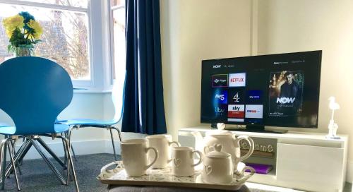 a living room with a tv and a tray with mugs at Coastal Apartment in Southend-on-Sea