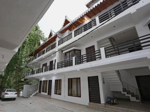 a white building with a car parked in front of it at Super Hotel O Summer King in Nainital