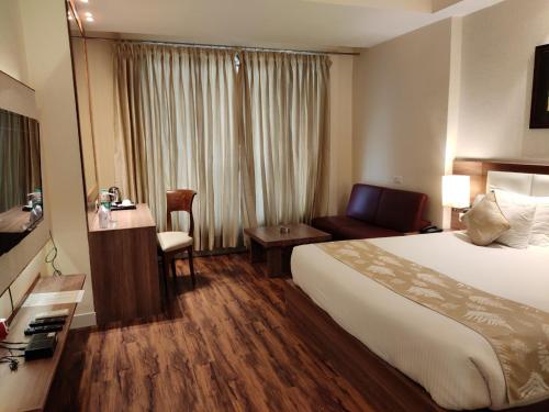 a hotel room with a bed and a desk and a chair at Sangai Continental (The Boutique Hotel) in Imphal