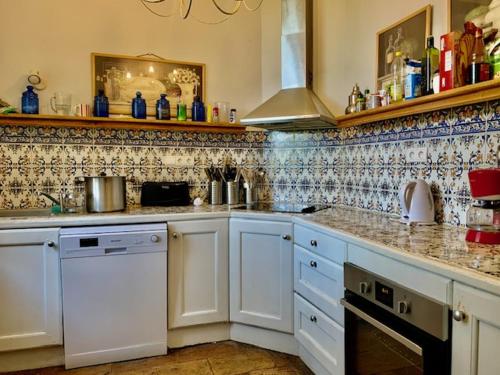 uma cozinha com armários brancos e uma parede de azulejos em MANOIR DE l'ARNAUDE em Fiac