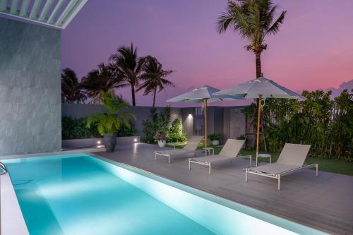 a swimming pool with lounge chairs and umbrellas at Beachfront Residences - Stunning Sea and Lake View in Bang Tao Beach