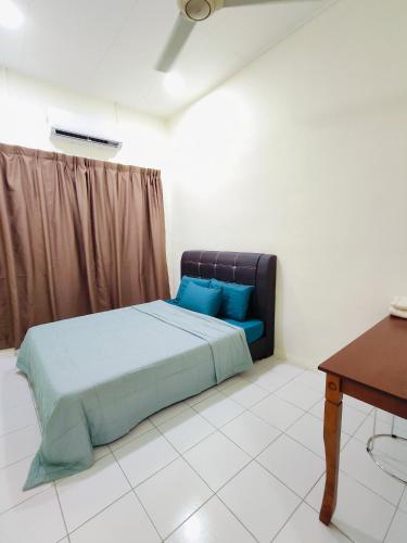 Schlafzimmer mit einem Bett mit blauen Kissen und einem Tisch in der Unterkunft 98 Homestay Sandakan in Sandakan