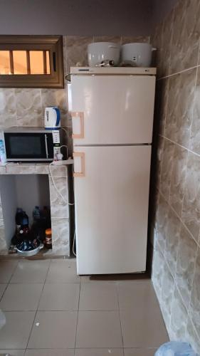 a white refrigerator in a kitchen with a microwave at Location meublée in Lomé